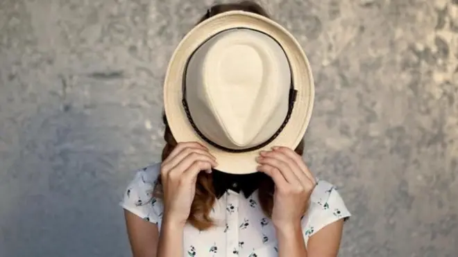 سيدة تخفي وجهها بقبعة 