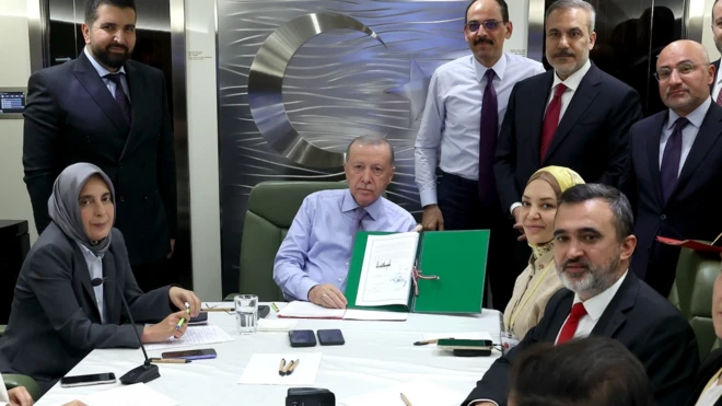 Cumhurbaşkanı Erdoğan bir mutabakatı kameraya göstererek attığı imzanın fotoğraflanmasını sağlıyor