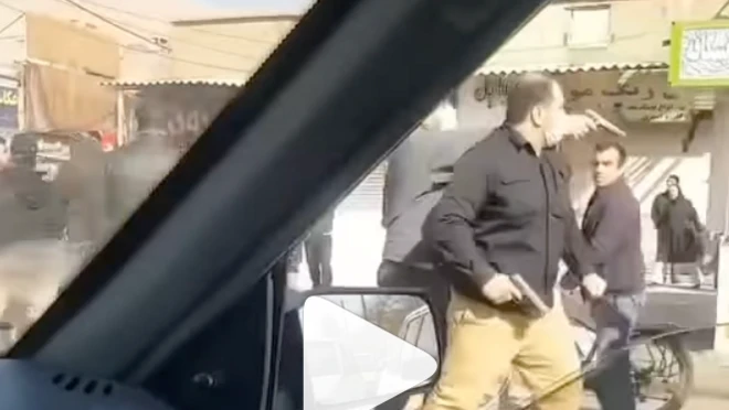 Una captura de pantalla de un video tomado desde un automóvil muestra a dos hombres armados vestidos de civil, uno de los cuales apunta directamente a alguien que se encuentra fuera del plano.