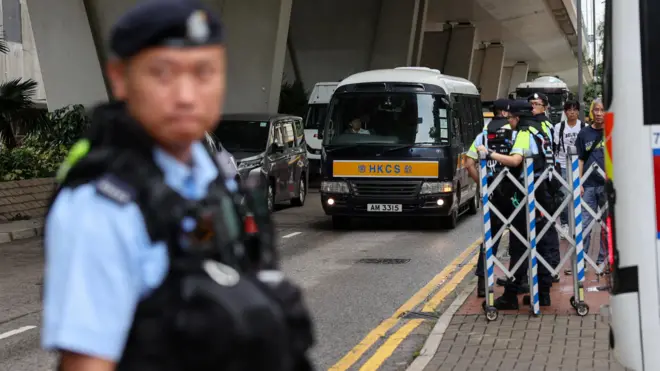 據信接載支聯會煽顛案被告人的香港懲教署囚車抵達西九龍裁判法院，多名身穿防刺背心的警員在法院停車場入口外站崗守衛（21/8/2026）