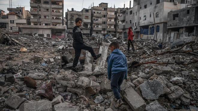 Meninos palestinos são vistos nos escombros de um prédio destruído por um ataque israelense em Rafah, Gaza, em 3 de janeiro de 2024