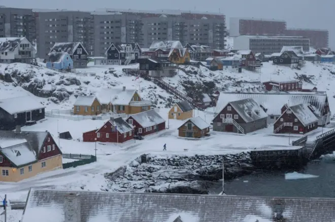 رجل يمشي مع كلبه في ميناء نوك القديم، غرينلاند، 18 يناير/كانون الثاني 2026.