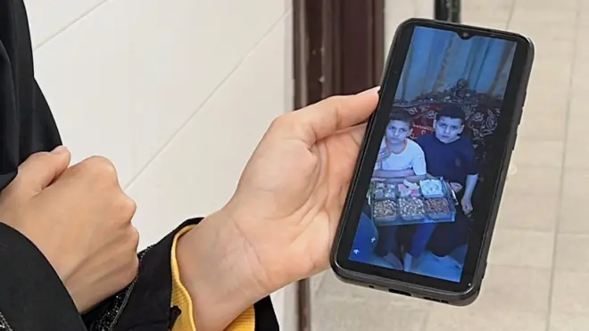 امرأة فلسطينية تعرض على هاتفها المحمول أطفال عائلة النجار الذين قتلوا في غارة جوية إسرائيلية في خان يونس جنوب قطاع غزة