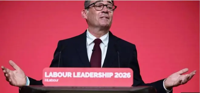 Andy Burnham bụ onye ndu otu Labour Party dịka o yi akwa ojii ma chile aka abụọ ya elu ka onye na-ekwu okwu