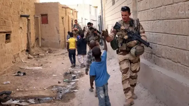 Soldats français salués par des enfants dans une rue au Mali.