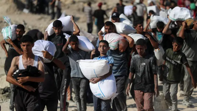 فلسطينيون يحملون مساعدات، في بيت لاهيا، شمال قطاع غزة، 2 أغسطس/آب 2025.