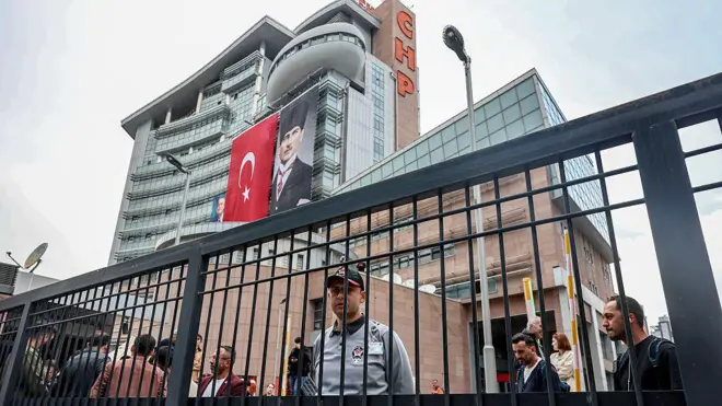 CHP genel merkezi önünde toplanmış insanlar ve üniformalı bir güvenlik görevlisi