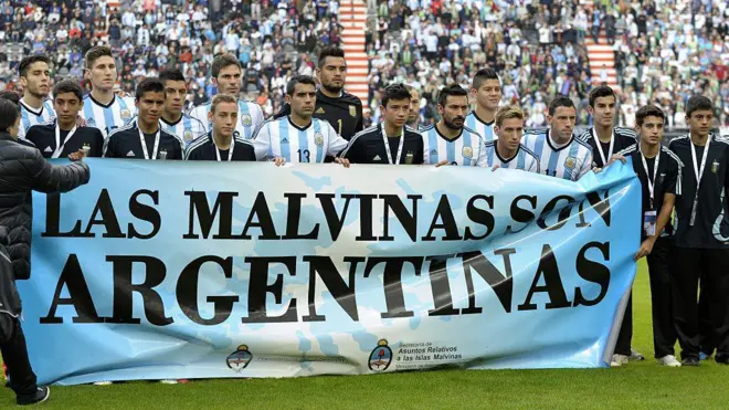La selección argentina tras una pancarta que dice "Las Malvinas son argentinas".