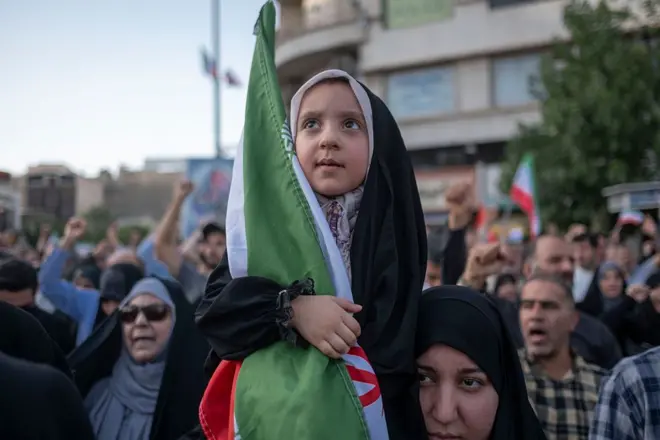 A veiled young Iranian girl holds a country flag during a protest to condemn the U.S. attacks on Iran's nuclear facilities in downtown Tehran, Iran, on June 22, 2025, amid the Iran-Israel war. (Photo by Morteza Nikoubazl/NurPhoto via Getty Images)