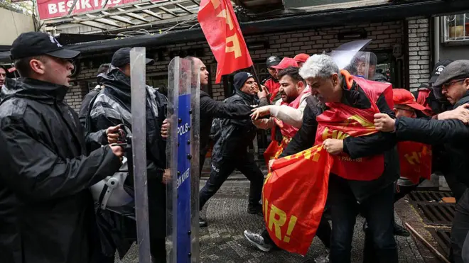 HKP üyeleri ve polisin karşı karşıya geldiği andan bir fotoğraf. Ellerinde bayrak ve üzerlerinde yelek olan parti üyeleri kalkanlı Çevik Kuvvet polisleri tarafından ittiriliyor.