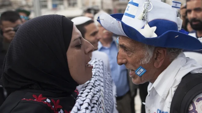 Pro-Palestinian woman wearing headscarf dey shout at one pro-Israeli man wey wear blue and white hat wit Israeli flag
