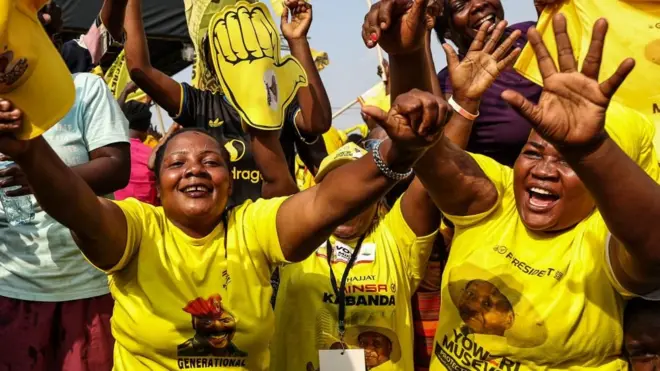 Two women in yellow T-shirts celebrate with outstretched arms