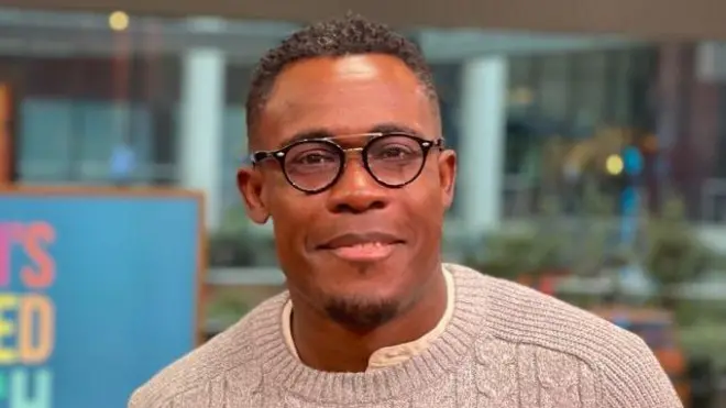 پیٹر کومولافے ٹیلی ویژن سٹوڈیو میں چشمہ پہنے ہوئے