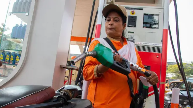 कोलकाता, भारत में 06 नवंबर 2022 को, एक पेट्रोल पंप की महिला कर्मचारी एक दोपहिया वाहन में फ्यूल नोज़ल लगा रही है
