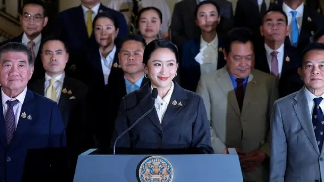 笑顔で演台に向かうスーツ姿のペートンタン首相。その左右と後ろに政府関係者が並んでいる