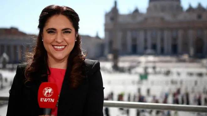Alvarado sosteniendo un micrófono de EWTN y de fondo la plaza y la Basílica de San Pedro.