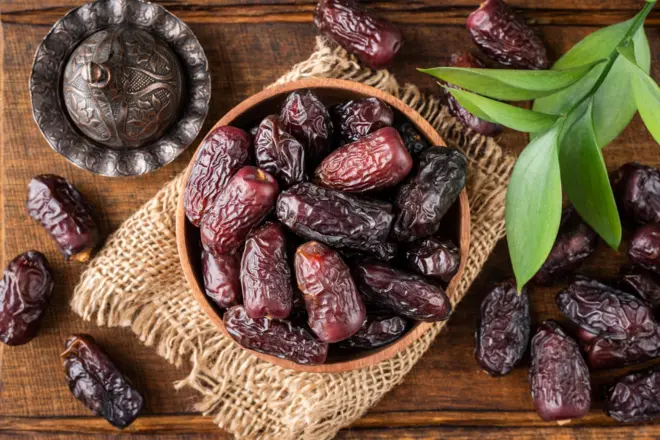 Dattes medjool séchées dans un bol sur fond de bois.