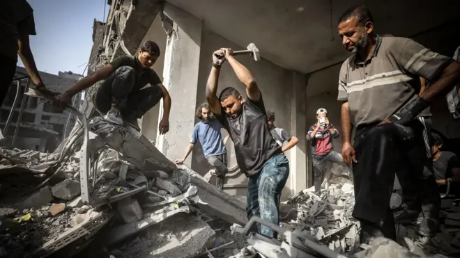 فلسطينيون يحاولون سحب جثة طفل تحت الأنقاض بعد هجمات إسرائيلية على مخيم الشاطئ غرب مدينة غزة