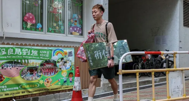 Dorz Cheung, a resident of Wang Fuk Court, carries family belongings, which he retrieved from his flat during his first return visit home since a deadly fire last year, in Hong Kong, China, April 21, 2026.