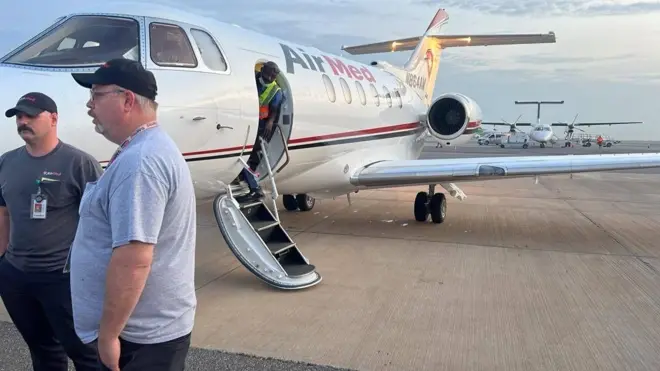 Two men stand beside one aircraft