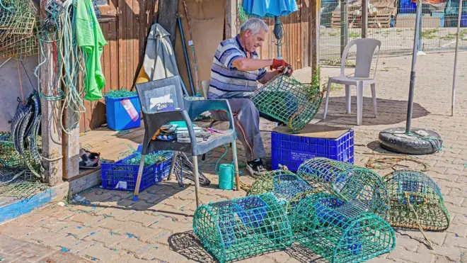 Pescador remendando armadilha para polvos no Algarve,aposta esportiva bonusPortugal