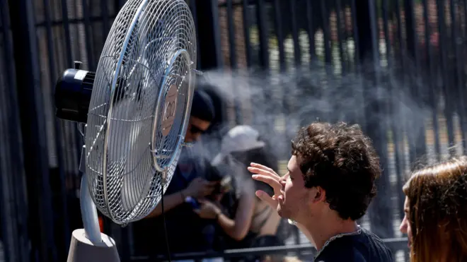 Ljudi se rashlađuju ispred ventilatora tokom toplih dana