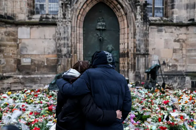 Мушкарац и жена загрљени гледају у свеће и цвеће