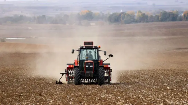 tarlada traktör süren bir çiftçi