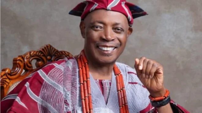 Ọba Rashidi Ladoja wọ aṣọ òfì agbada ati sokoto alawọ waini ti a mọ si Alaari, o dé fìlà abetíajá, wọ ilẹkẹ mẹta sọrun, o na ọwọalaafia rẹ soke bii igba to di ikuuku, tó sì ń rẹ́rìn-ín