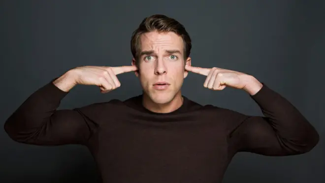 Un hombre se tapa los oídos con las manos.