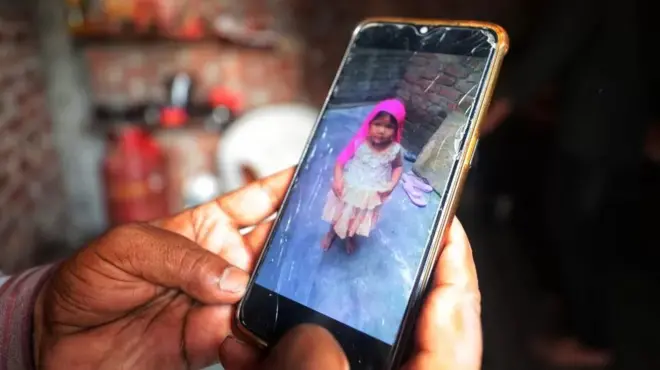 Main tenant un portable sur laquelle se trouve une photo d'enfant.