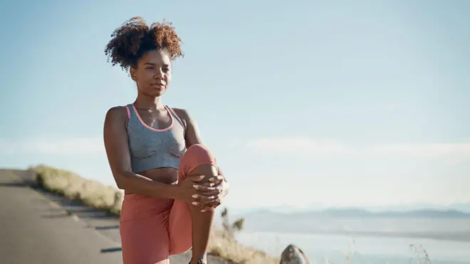 une femme fait des exercices pour les genoux sur une plage.