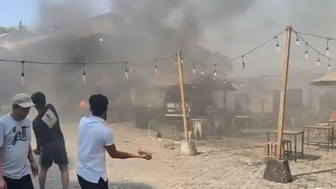 Warga terlihat melempari bangunan yang terbakar saat bentrokan di Jalan Tambak I, Menteng, Jakarta Pusat, Minggu (26/07). 