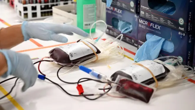 Две јединице крви, медицински шприцеви и руке медицинског радника