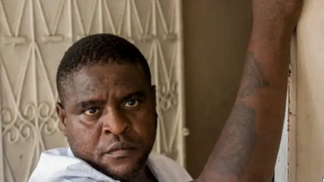 Jimmy Chérizier in a doorway, clutching a wall