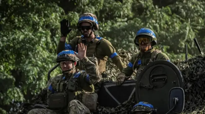 Three Ukrainian soldiers sit on top of tank in Sumy region
