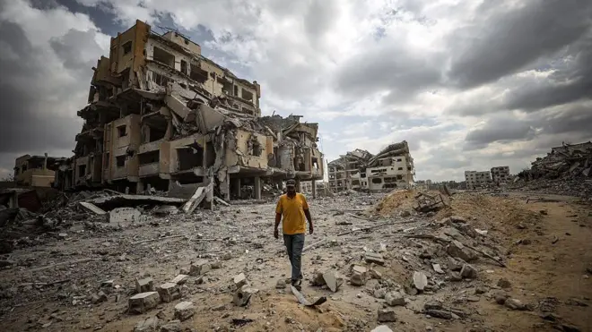 Una persona camina entre escombros de edificios en Gaza