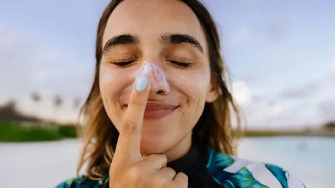 Una mujer se coloca protector solar en la nariz