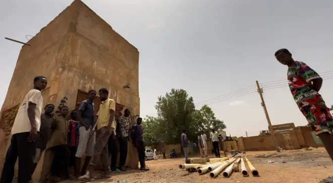 أطفال وشباب سودانيون يقفون أمام أنابيب تعرضت للتخريب بسبب الحرب الجارية.