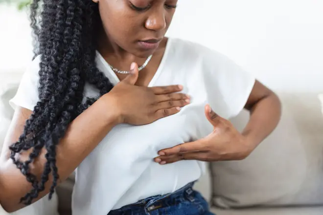 Jeune femme afro-américaine palpant son sein par elle-même qu’elle s’inquiète du cancer du sein.