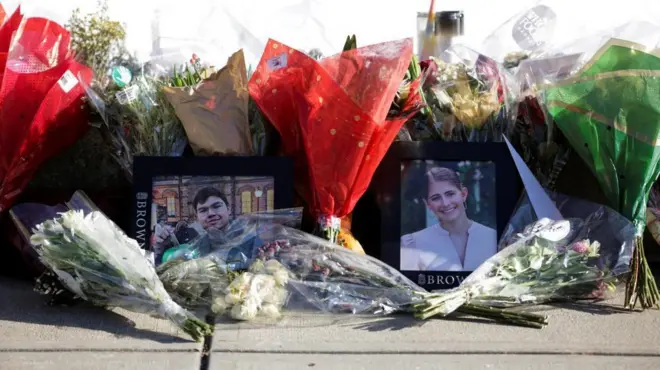 エラ・クックさんとムハンマド・アジズ・ウムルゾコフさんの写真が「BROWN」の文字が入った写真フレームに入れられて置かれている。周囲には、透明、赤色、緑色の包装に巻かれた花束が多数置かれている