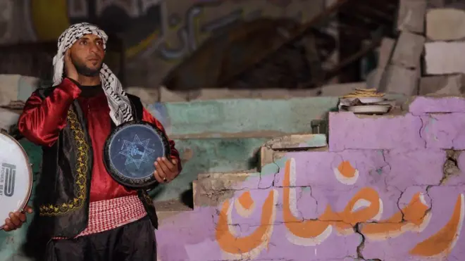 المسحراتي يسير في شوارع خام يونس المدمرة لإيقاظ الفلسطينيين لتناول وجبة السحور الأولى في شهر رمضان المبارك، فجر 1 مارس/آذار 2025