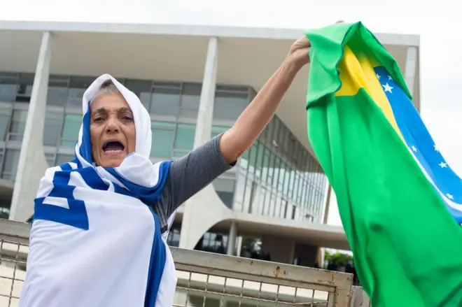 Manifestante enrolada na bandeiraempresa de aposta esportivaIsrael segura uma bandeira do Brasilempresa de aposta esportivafrente ao prédio do STF