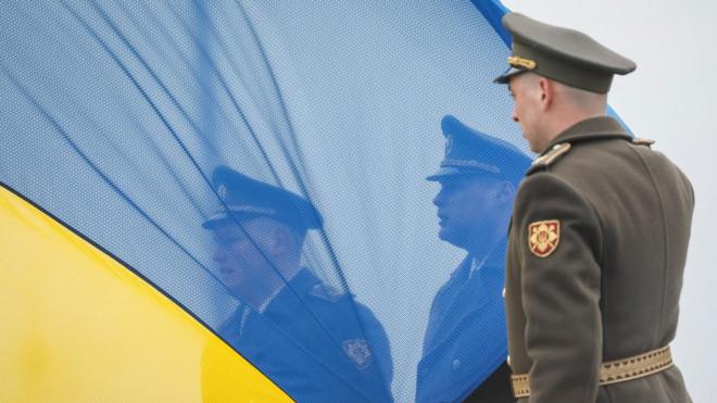 Soldado passandoblaze efrente à bandeira da Ucrânia