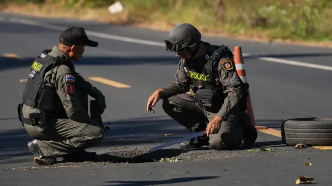 Два солдата рассматривают воронку в дорожном покрытии