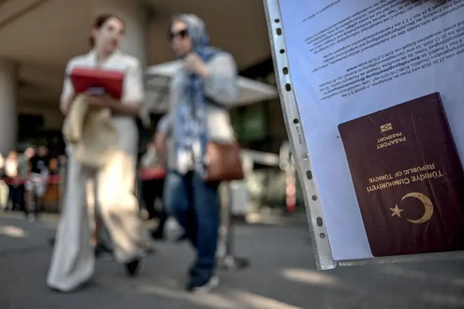 30 Haziran 2026 tarihinde İstanbul'da Schengen vizesine başvurmak üzere vize başvuru merkezinin önünde sıra bekleyen insanların olduğu bir ortamda, Türk vatandaşı bir vize başvuru sahibinin pasaportu görülüyor. Avrupa Komisyonu tarafından yayınlanan verilere göre, 2025 yılında Türkiye'den Schengen Bölgesi'ne (çoğunluğu Avrupa Birliği üyesi olan 26 ülke) yapılan 1,25 milyon vize başvurusunun 1,07 milyonu onaylanmıştır.