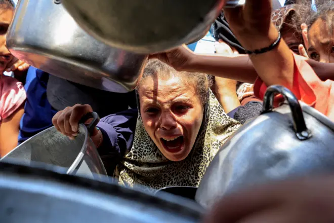 طفلة غزية تمد وعاء لطلب الطعام، 21 أغسطس آب 2025