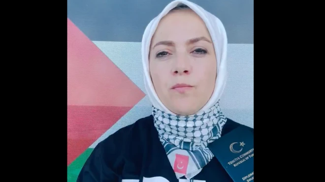 Beyaz başörtülü bir kadın türk pasaportunu da elinde tutarak konuşuyor