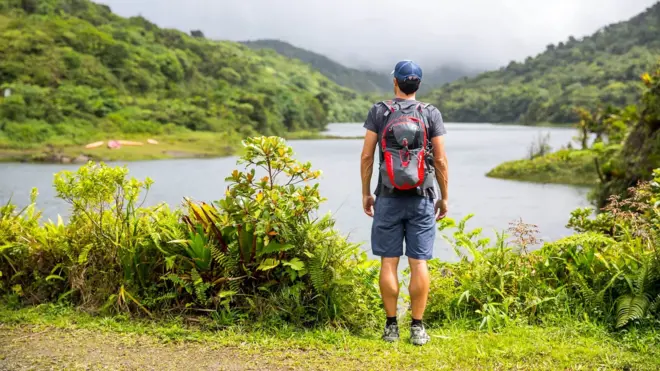 배낭을 메고 눈앞의 강과 산을 바라보는 한 남성