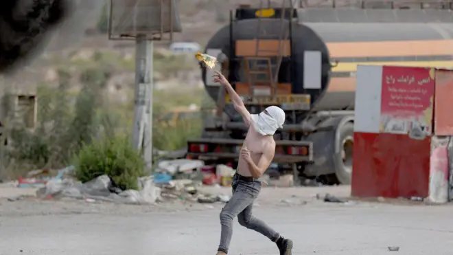 Um homem joga um coquetel molotov enquanto palestinos entramplataforma betanoconfronto com as forças israelenses no distritoplataforma betanoBeit El,plataforma betanoRamallah, Cisjordânia, 